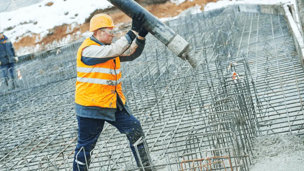 Betongarbetare gjuter armerad grund med betongpump på byggarbetsplats
