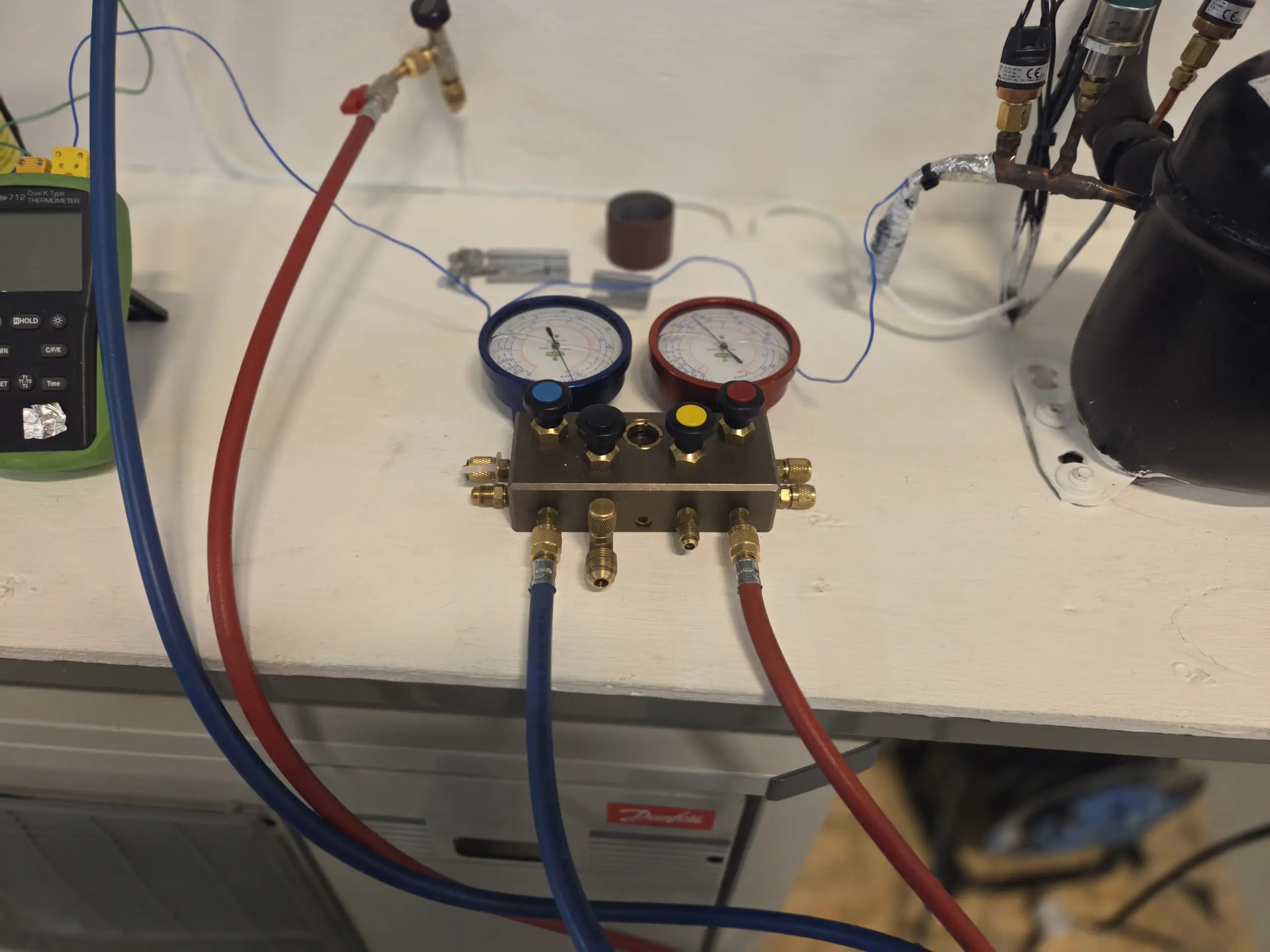 En kyl- och värmepumpmontör arbetar med installation och service av kylsystem och värmepumpar. På bilden syns manometrar, slangar och teknisk utrustning kopplade till ett kylaggregat i en professionell arbetsmiljö. Arbetet kräver precision, teknisk kunskap och erfarenhet inom kylteknik och energieffektiva lösningar.
