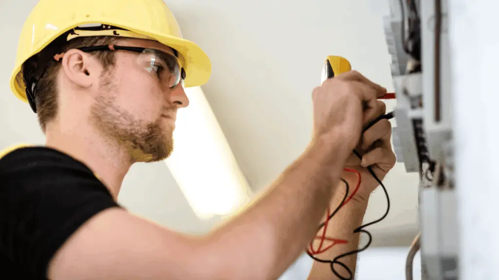 installationselektriker i gul hjälp hanterar kablar till ett elskåp