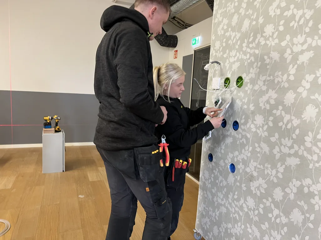 Två elever arbetar tillsammans med elinstallation i en utbildningslokal på Movant Varberg.