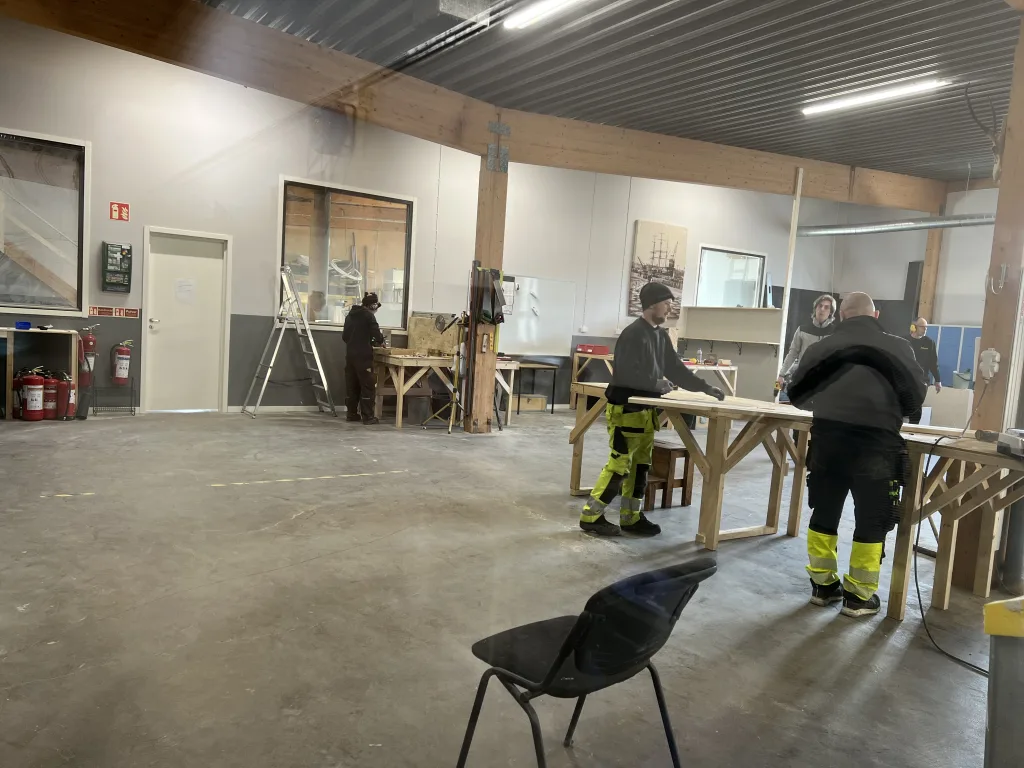 Flera elever arbetar med träprojekt vid bänkar i Movant Varbergs byggverkstad.