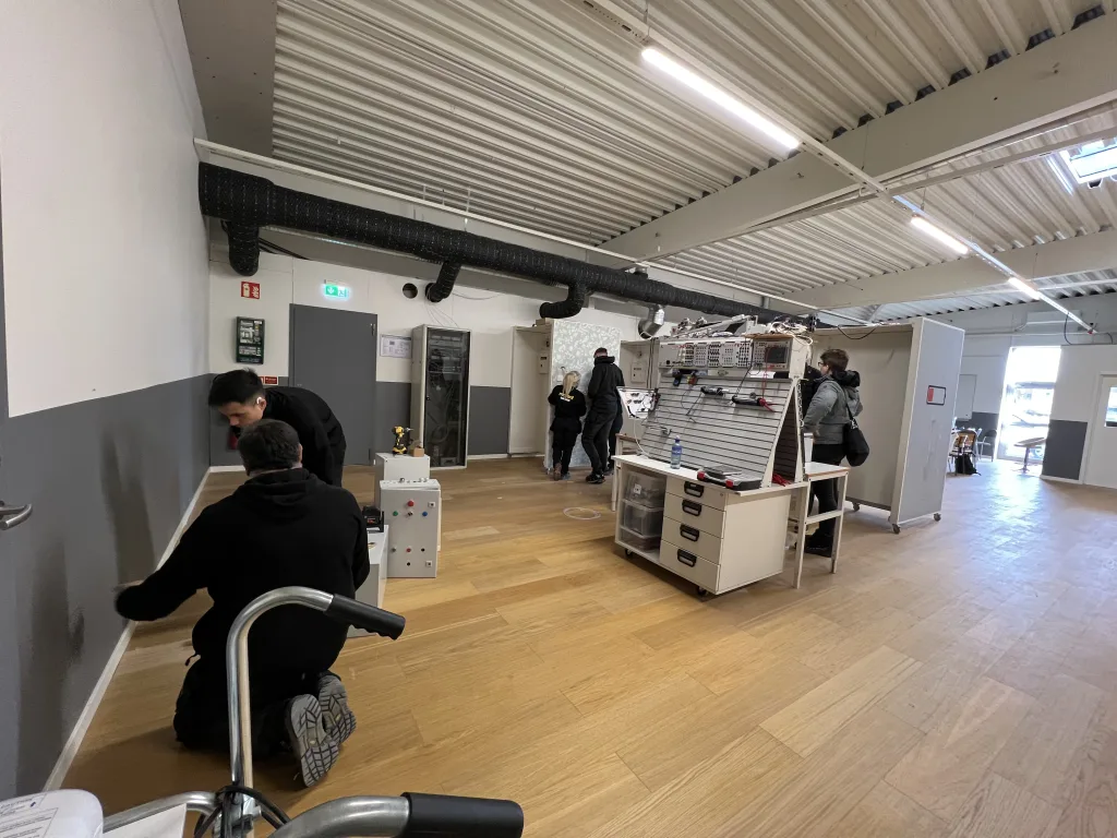 Översikt av el- och teknikverkstad på Movant Varberg med flera elever i arbete.
