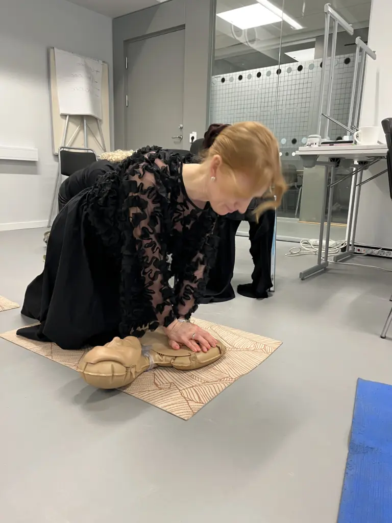 En deltagare genomför bröstkompressioner på en övningsdocka under en HLR-utbildning hos Movant. Momentet sker på golvet i ett klassrum med fokus på praktisk träning.